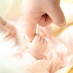 Aikuisen käsi pitelee vauvan kättä